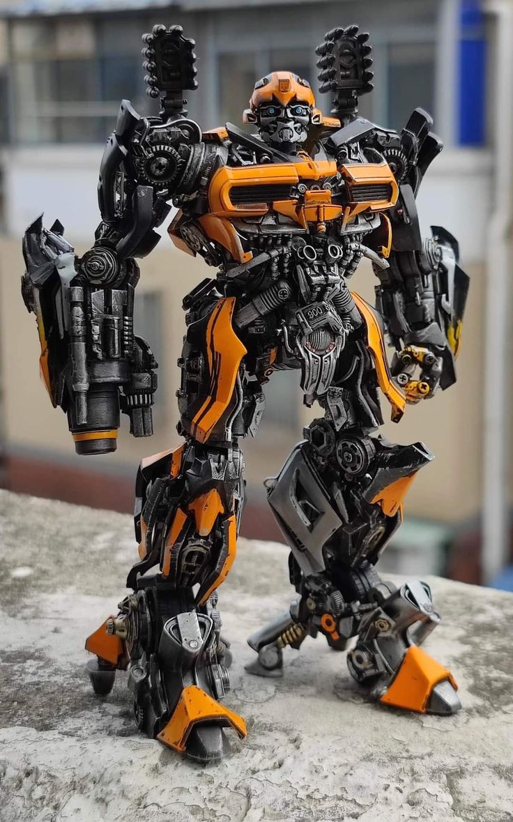 an orange and black robot standing on top of a rock