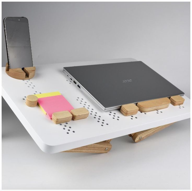 a laptop computer sitting on top of a white table next to a cell phone and sticky pad