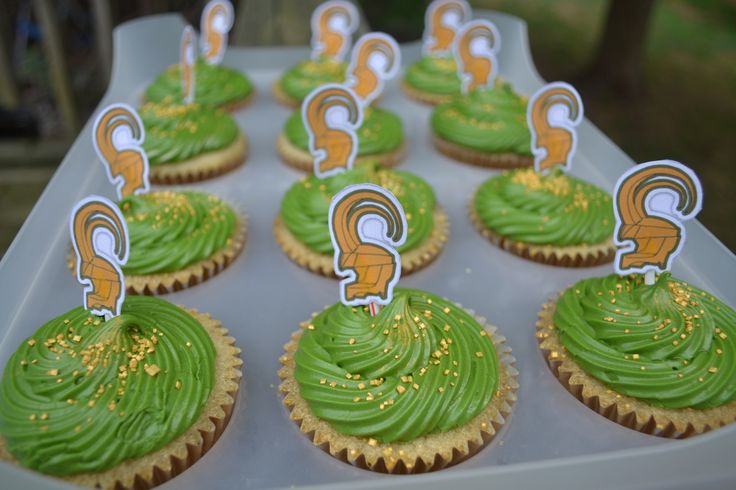 cupcakes with green frosting and gold sprinkles on a tray