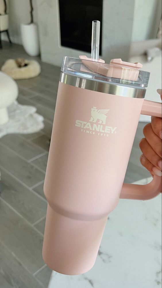 a person holding a pink tumbler cup in their hand with the word stanley on it