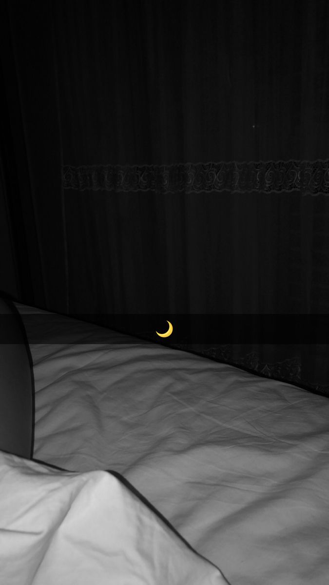 a black and white photo of a bed with the moon in the dark behind it