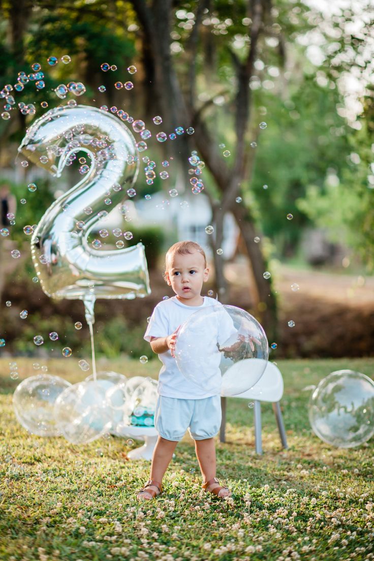 a little boy standing in the grass with bubbles and numbers 2 on it's back