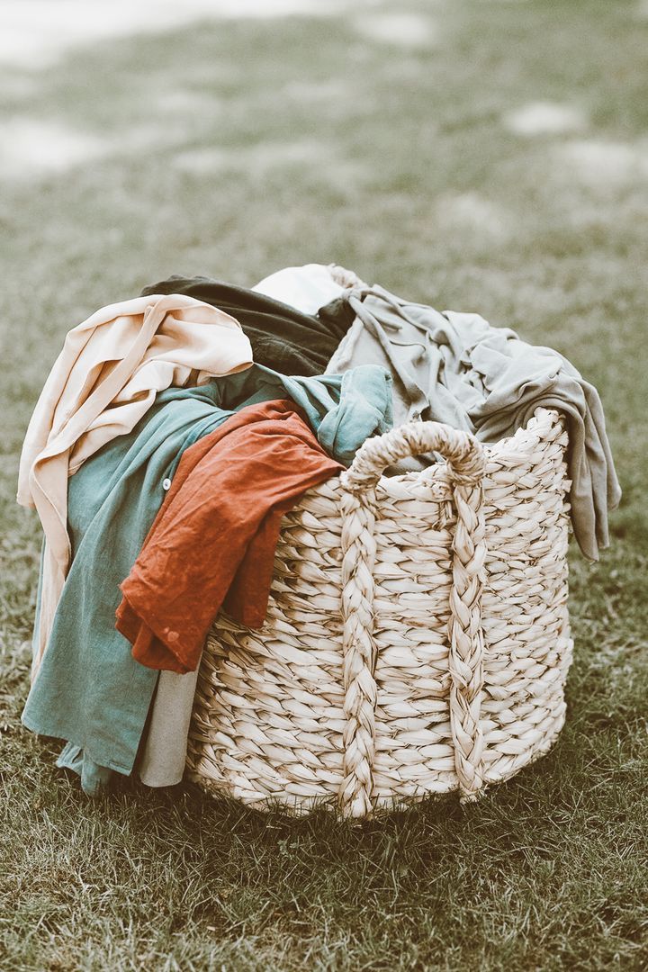 a basket filled with clothes sitting on top of a lush green field