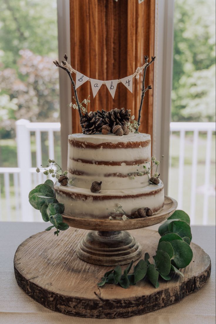 a three tiered cake sitting on top of a wooden table next to a window