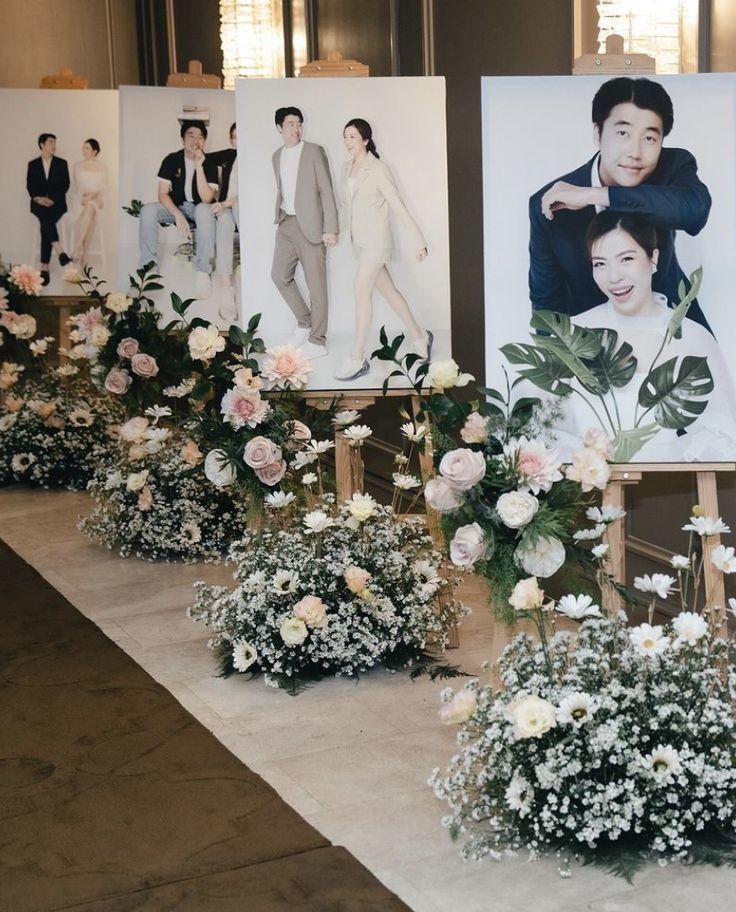 a bunch of flowers that are sitting in front of pictures on the wall behind them