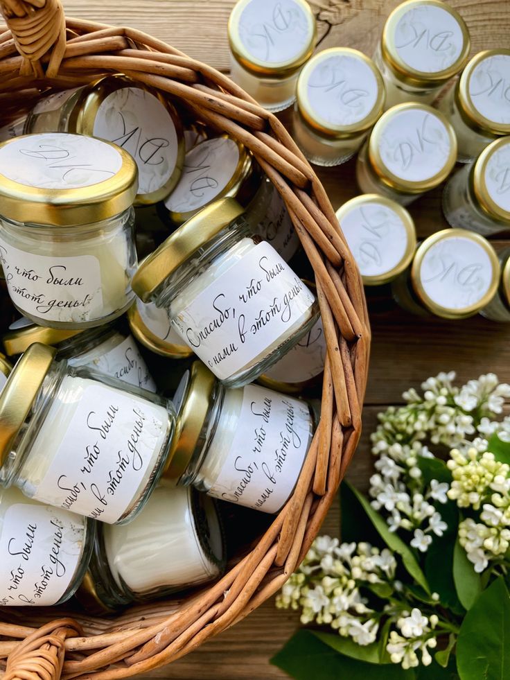 a basket filled with lots of small jars next to flowers and some candles on top of a table