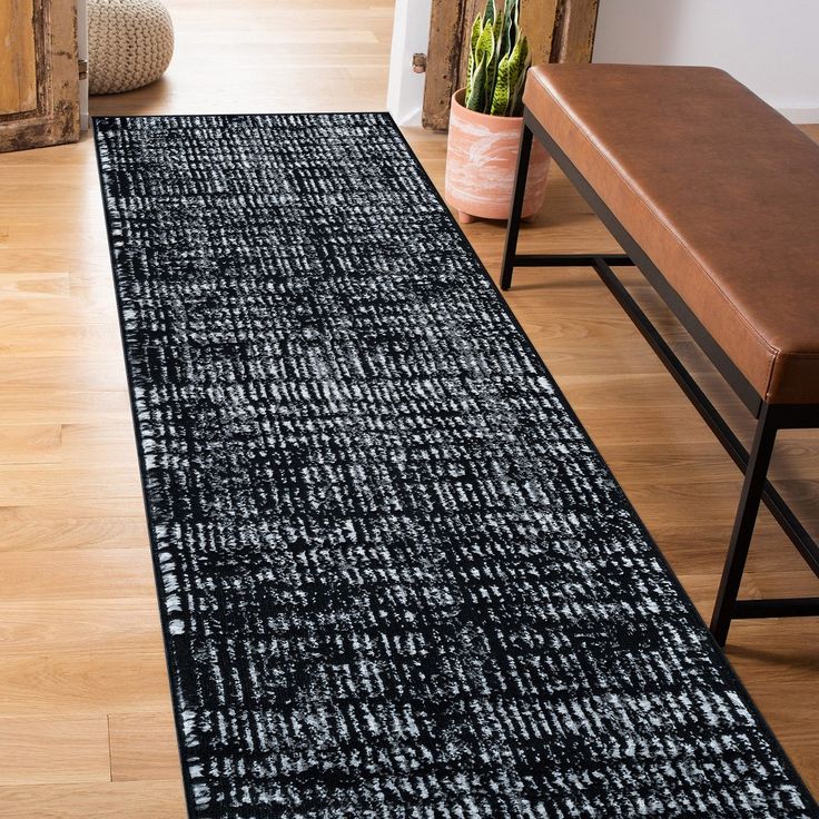 a black and white runner rug on the floor next to a bench in a living room