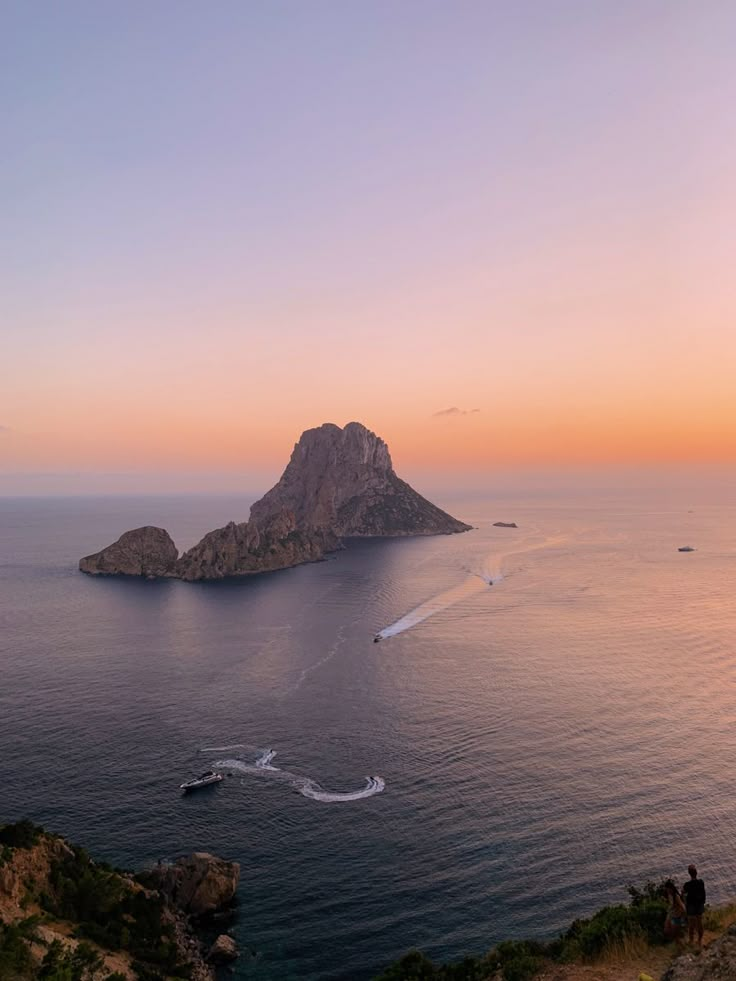 an island in the middle of the ocean at sunset