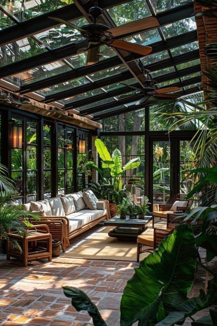 a living room filled with lots of plants and furniture under a glass roofed ceilinged area