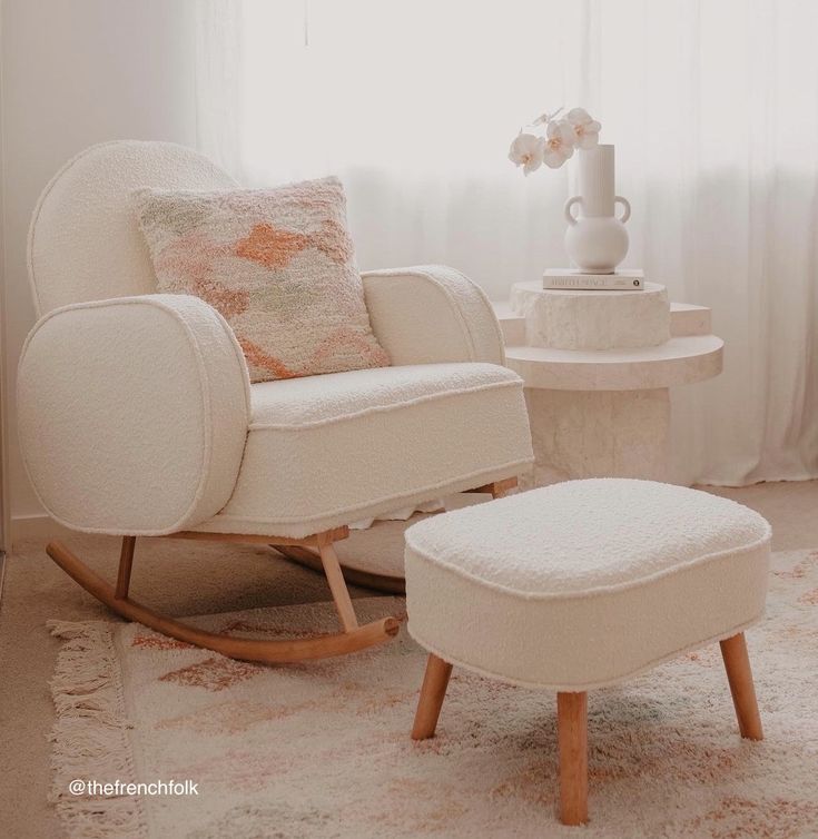 a living room with a chair, ottoman and coffee table in front of a window