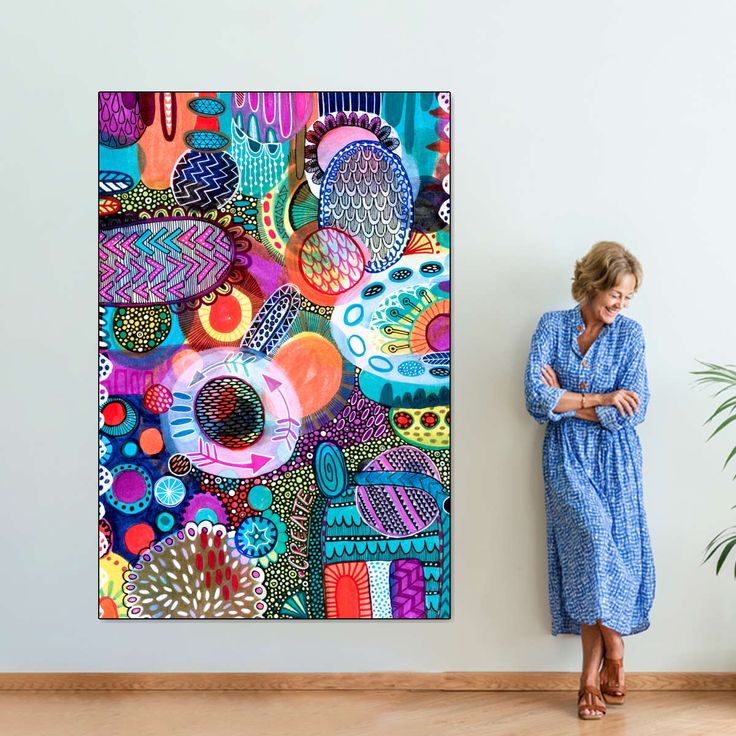 a woman standing in front of a painting on the wall next to a plant and potted plant