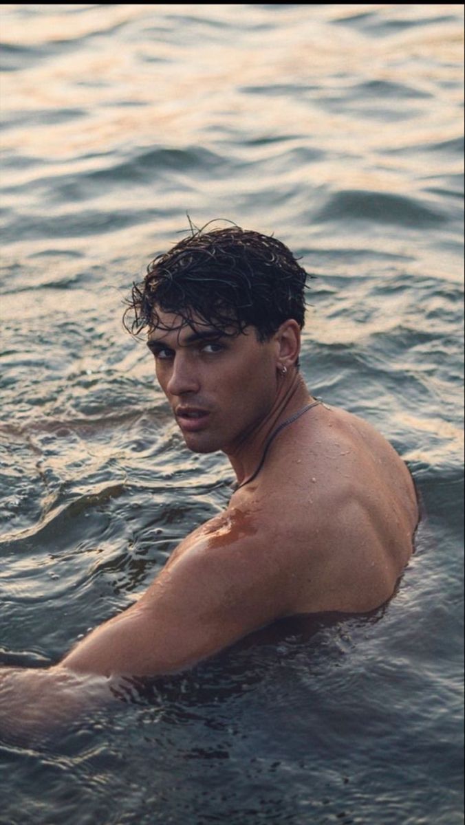 a shirtless man swimming in the water