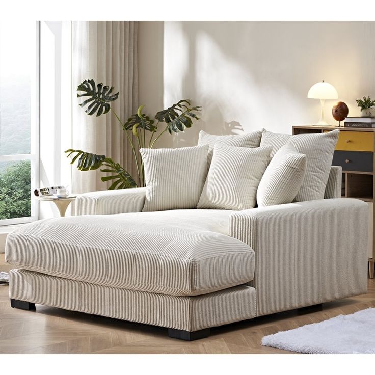 a living room with a white couch and some plants in the corner by the window