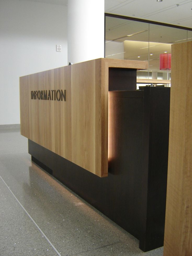 the reception desk is made out of wood and has an illuminated sign that reads information