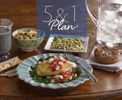 a wooden table topped with plates and bowls filled with different types of food next to a glass of water