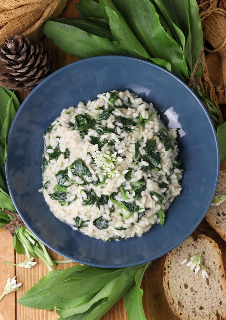 a blue bowl filled with riso and spinach on top of bread next to green leaves