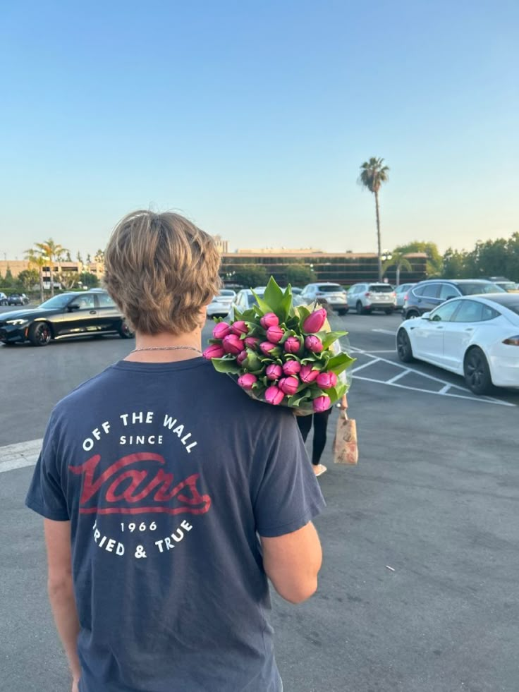 a man in a parking lot with flowers on his shoulder and the back of his head