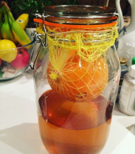 a jar filled with liquid sitting on top of a table next to bananas and oranges