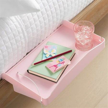 a pink tray with two notebooks and a drink on it next to a bed