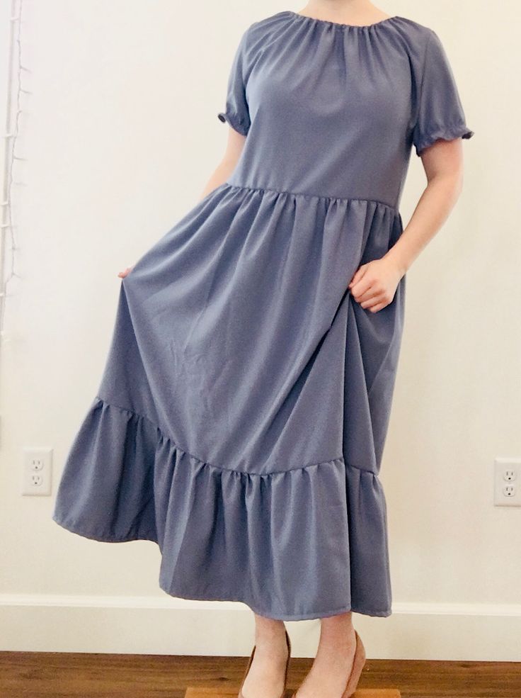 a woman standing on top of a wooden floor wearing a dress with ruffles