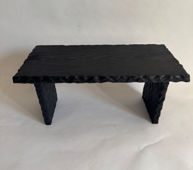 a black wooden bench sitting on top of a white background