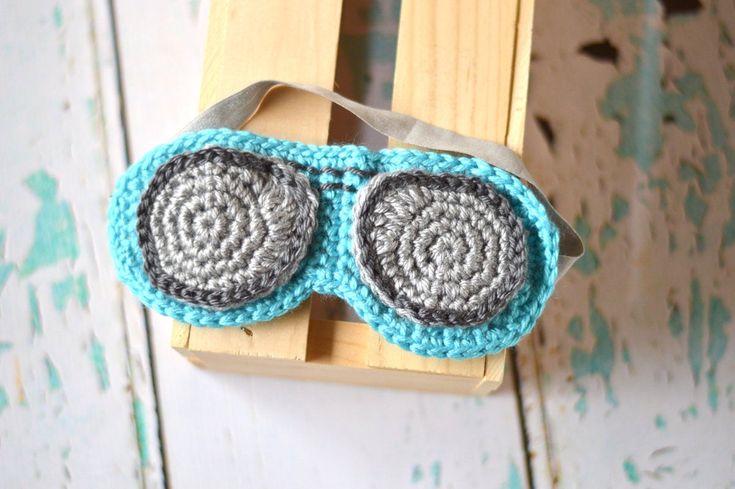 a crocheted eye mask hanging from a wooden sled