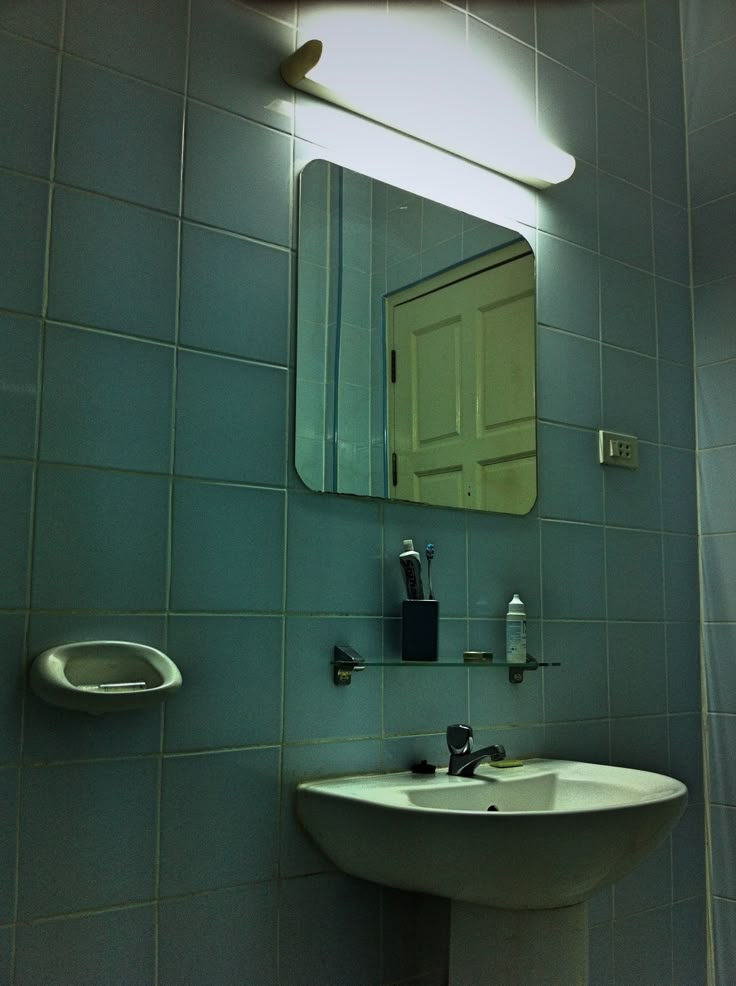 a bathroom with a sink, mirror and soap dispenser on the wall