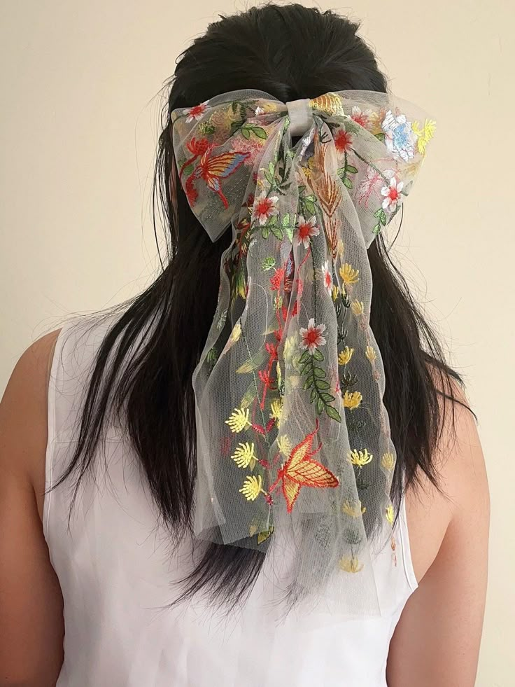 the back of a woman's head wearing a sheer scarf with flowers on it