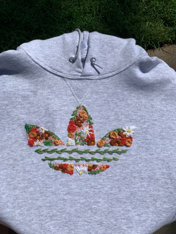 the adidas hoodie is embroidered with flowers and leaves on it's chest