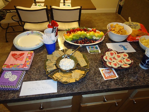 a table filled with food and snacks on top of a granite countertop next to chairs