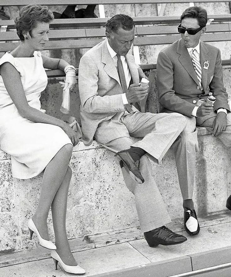 two men and a woman sitting on a bench