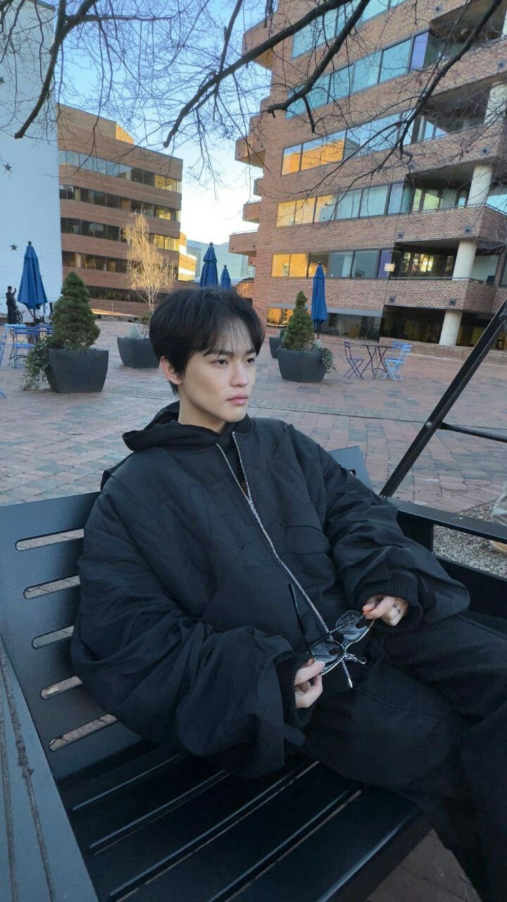 a young man sitting on top of a black bench