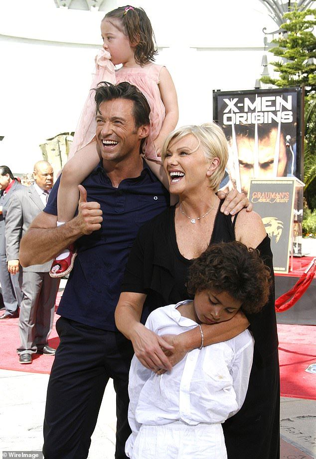 two adults and one child posing on the red carpet