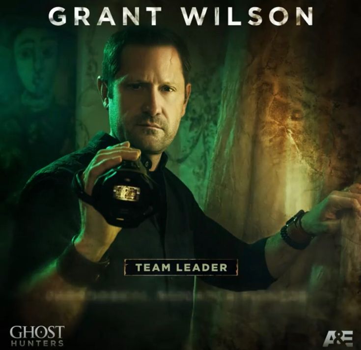 a man holding a camera in front of a green background with the words team leader on it