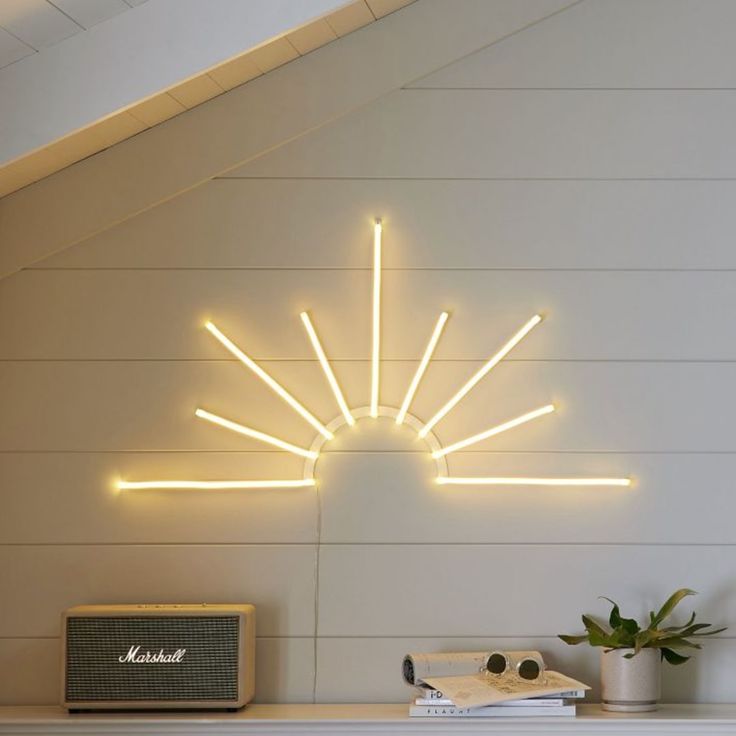 a white fireplace with a neon sunburst on the wall above it next to a radio