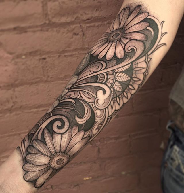 a woman's arm with flowers and swirls tattooed on the side of her leg