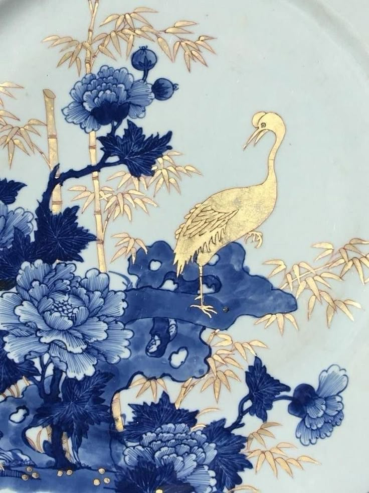 a blue and white plate with flowers and a bird on it's side,