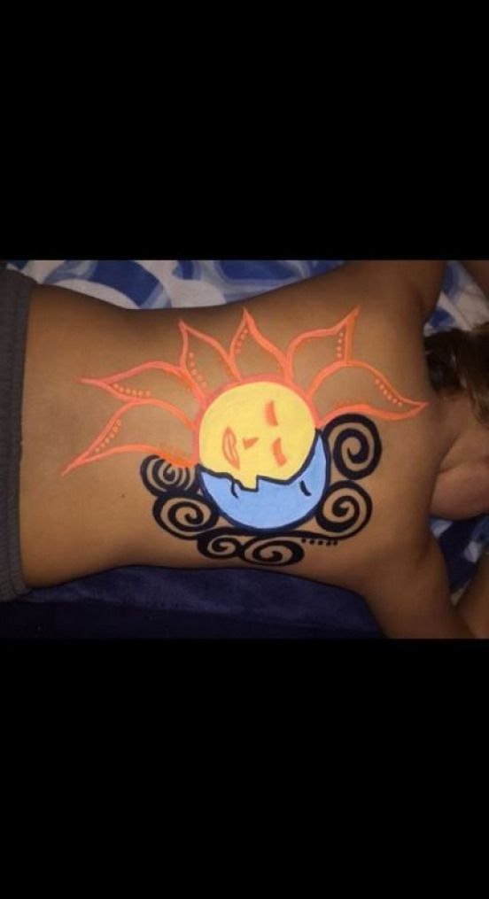 a woman laying on top of a bed covered in sun and clouds tattoo designing her stomach