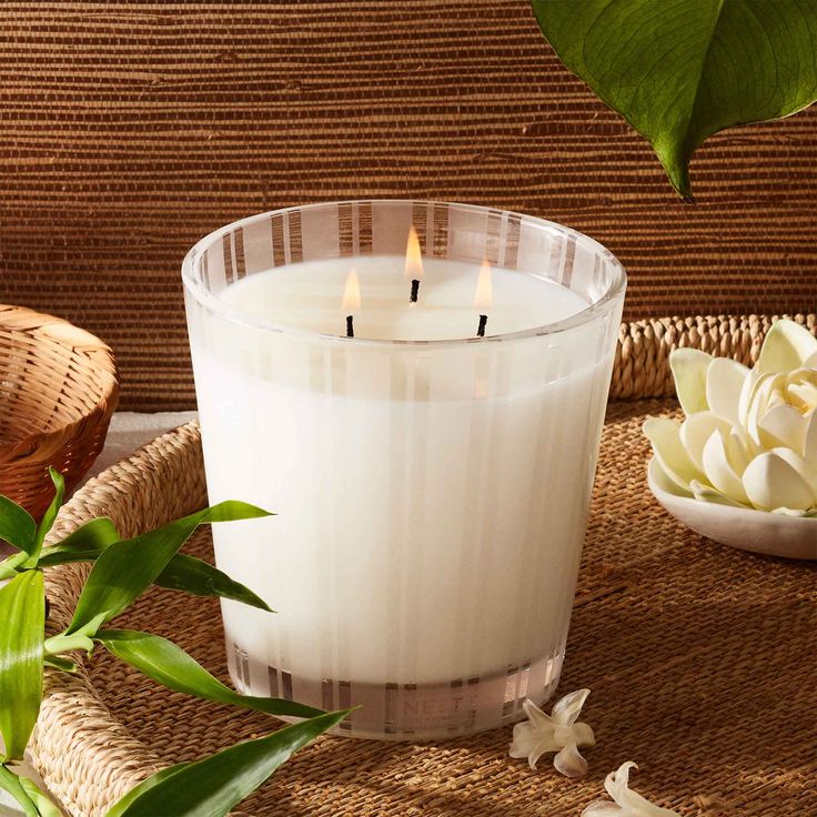 a white candle sitting on top of a table next to a basket with flowers in it