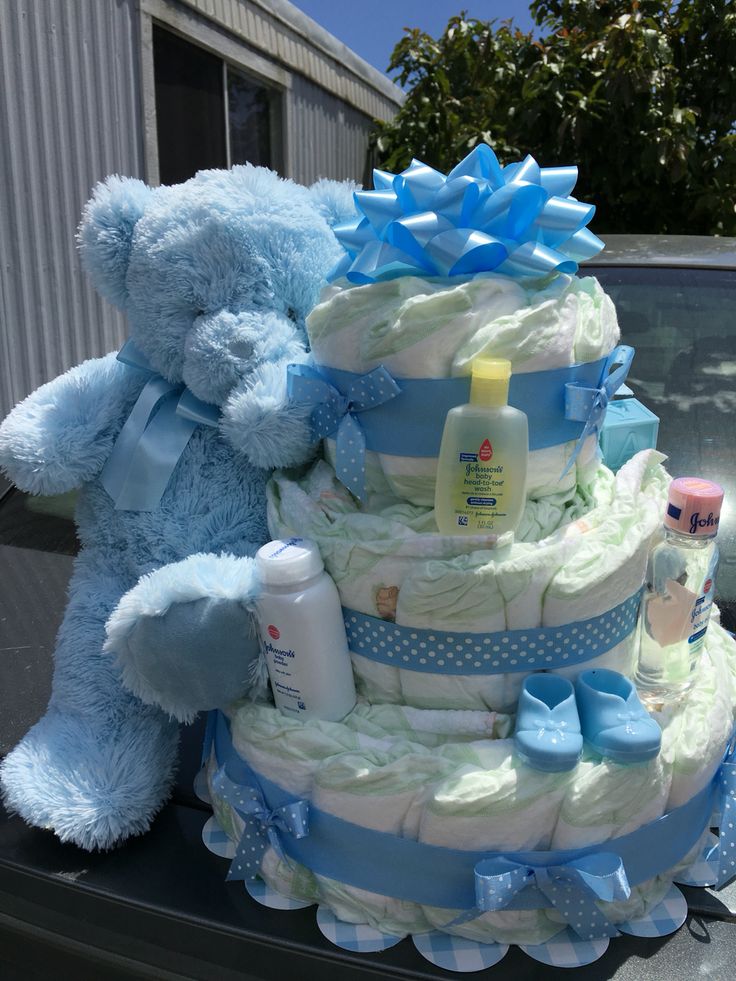 a large blue teddy bear sitting on top of a baby shower cake in the back of a car