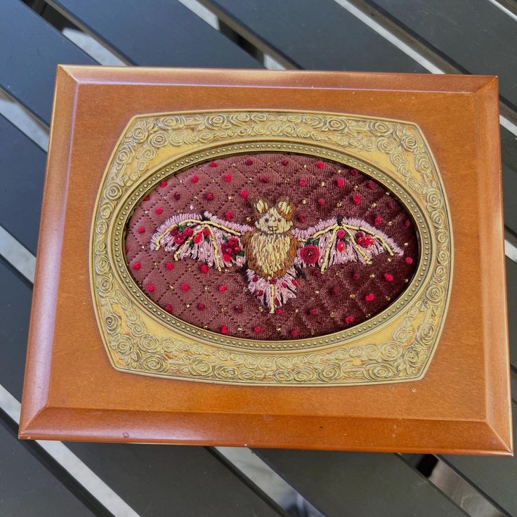 a wooden frame with an embroidered owl on it