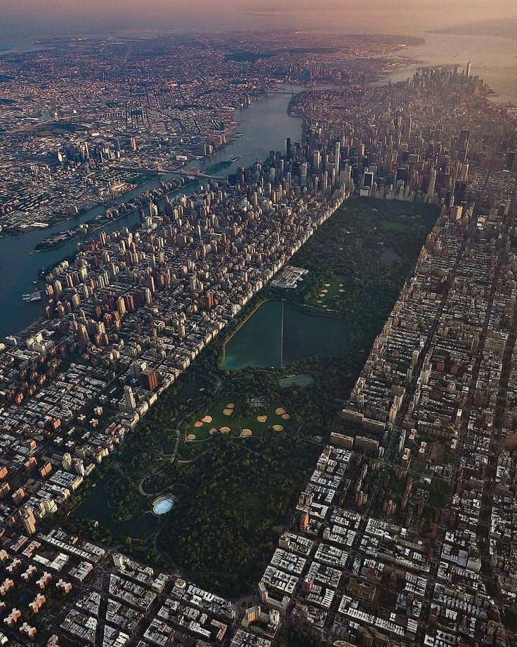 an aerial view of a large city with lots of tall buildings and water in the background