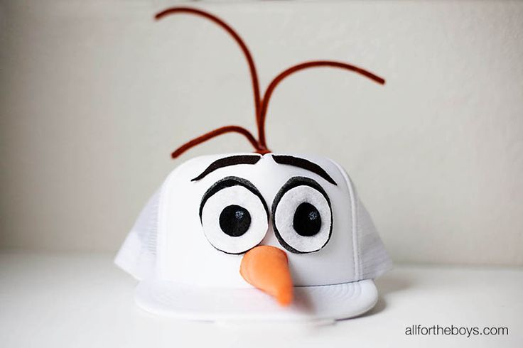 a white hat with an orange nose and black eyes on it's face, sitting on top of a table