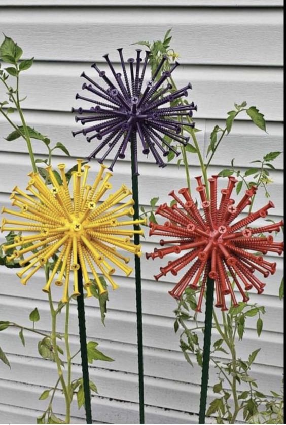 three different colored flowers in front of a white building