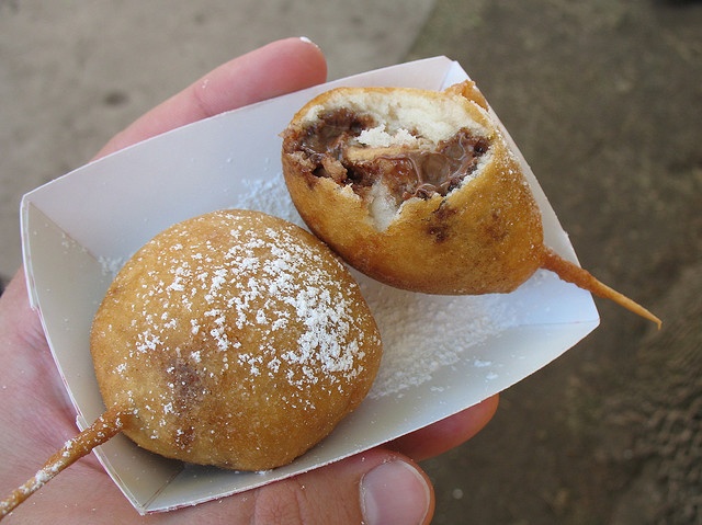 two pastries sitting on top of each other in a white paper container with powdered sugar