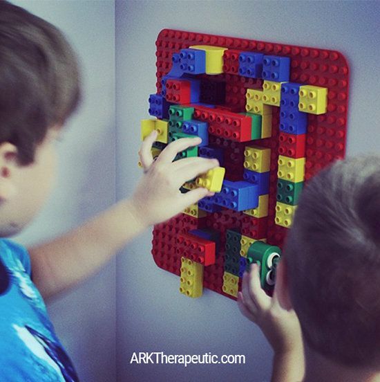 two young boys playing with legos on the wall