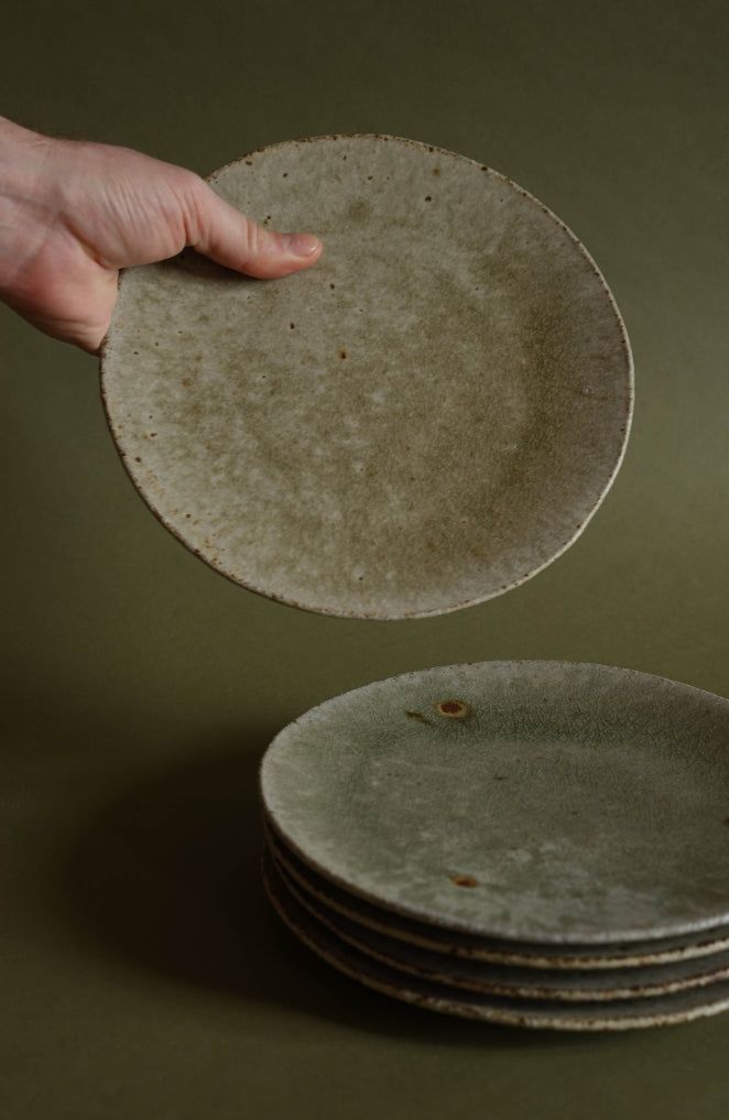 a hand reaching for a stack of plates