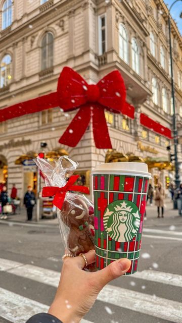 a person holding up a starbucks cup with chocolates in it and a red bow