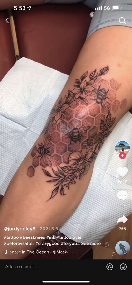 a woman's leg with flowers and honeycombs on it, in the middle of her arm