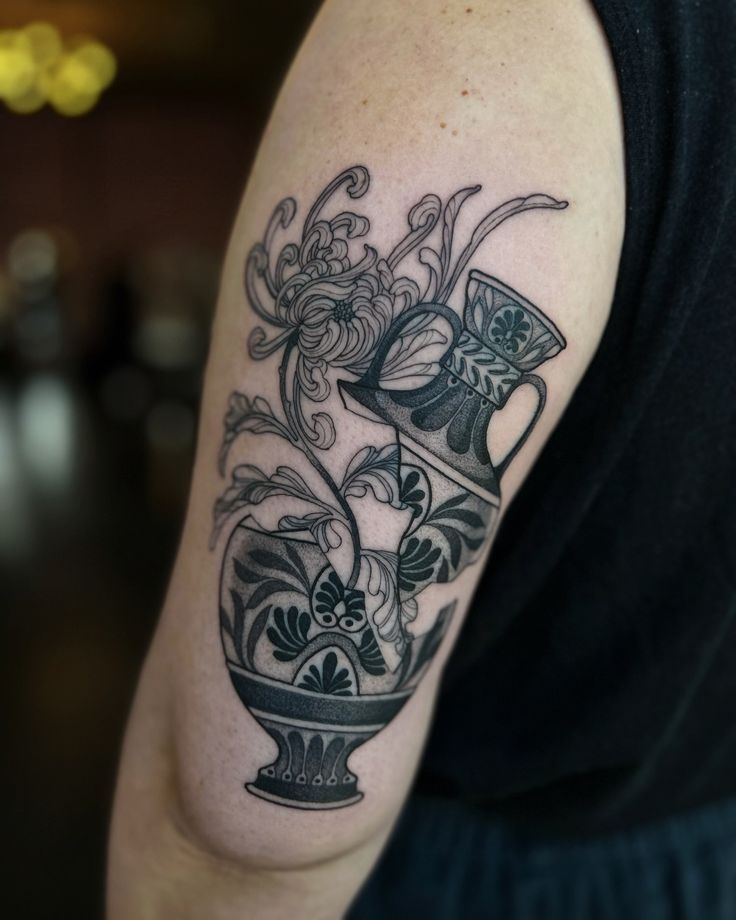 a black and white photo of a vase with flowers on it's arm tattoo